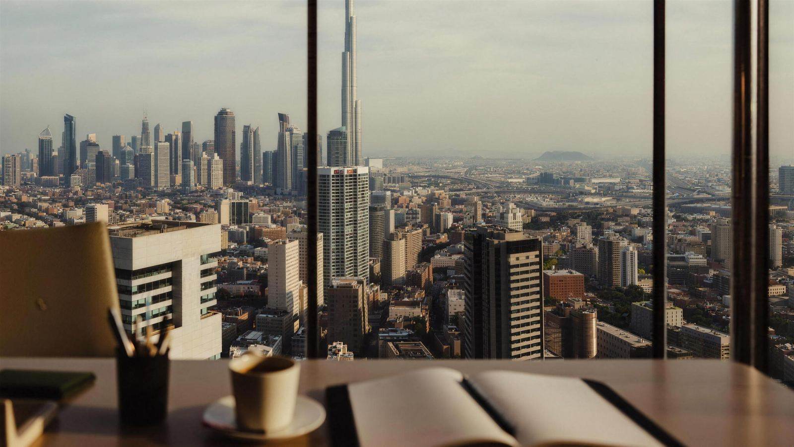 Downtown Dubai and the Burj Khalifa seen from inside an office, a desk in the foreground