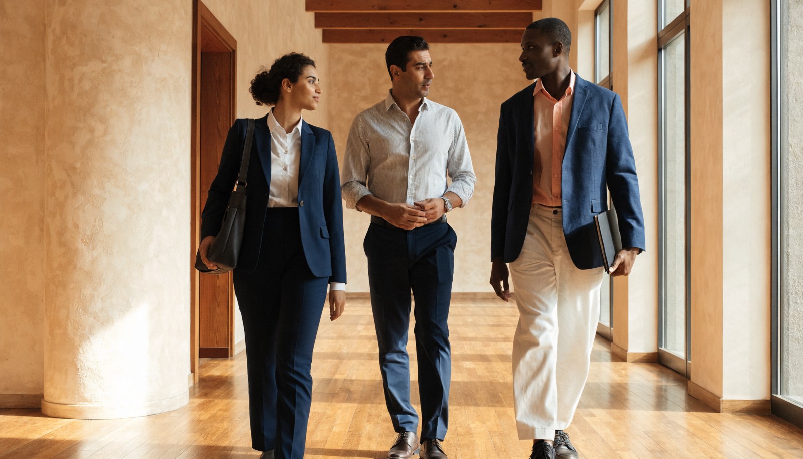 Three colleagues in conversation in an office corridor.