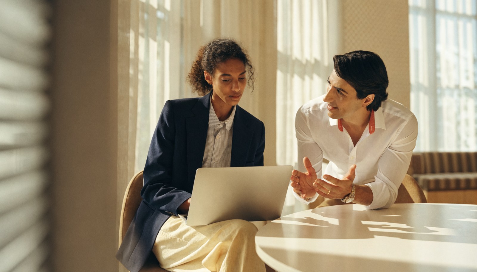 A client meeting an adviser beside a laptop.