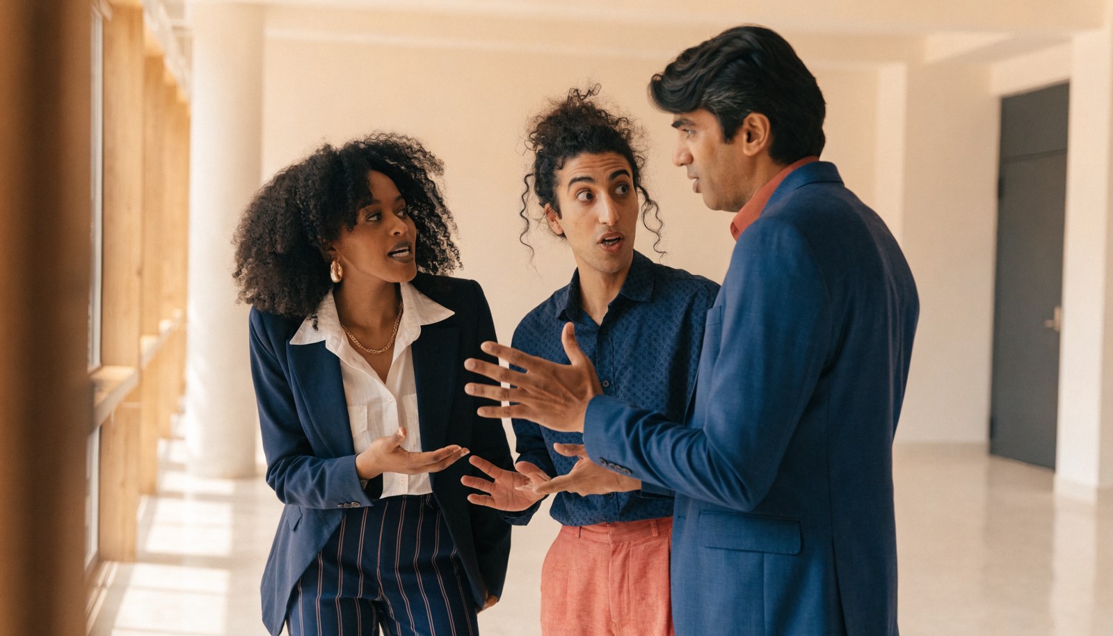 Three colleagues discuss a change programme in a bright office corridor.